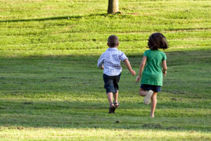 a-little-boy-and-girl-run-through-the-grassy-field-image